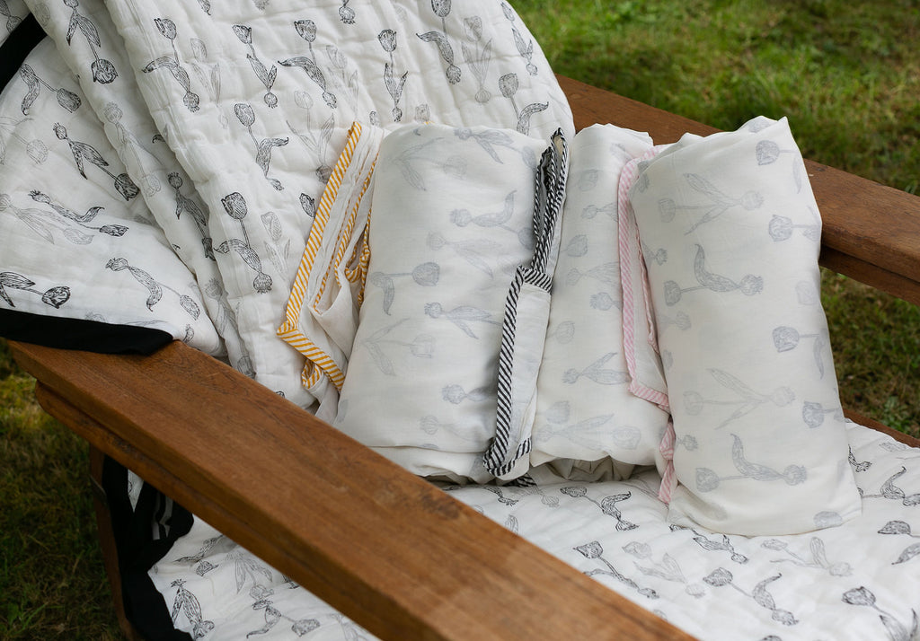 Rolled up Dohar blankets on a planters chair in the garden 