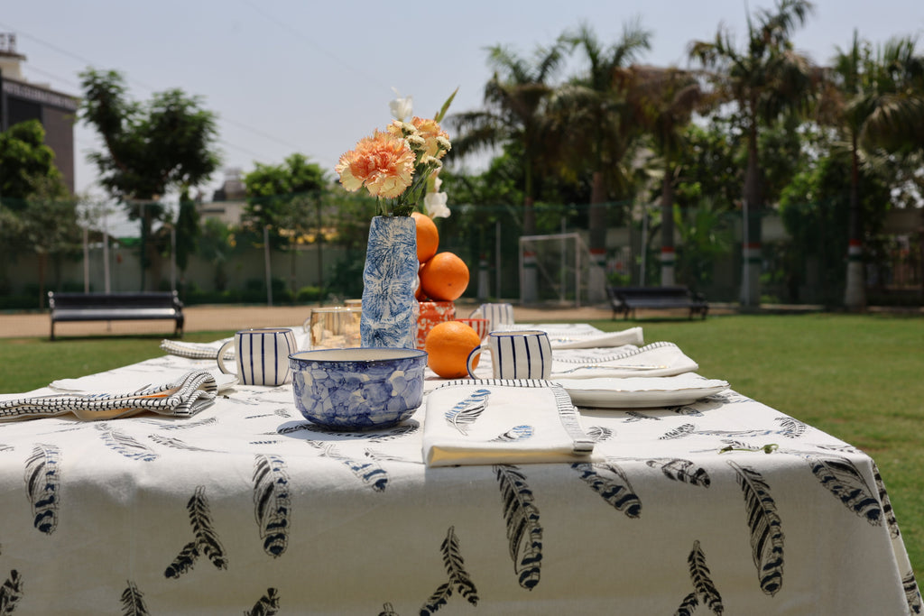 a table set with a jay feather tablecloth and orange accessories