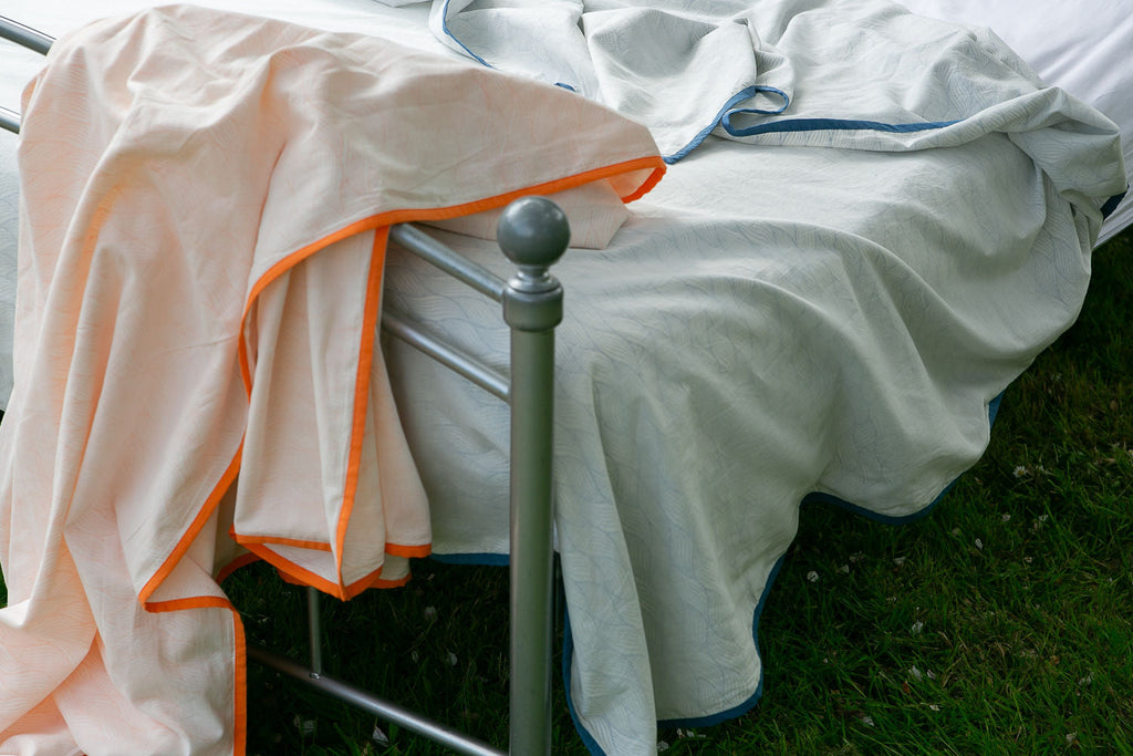 close up of two Indian dohar blankets draped on a bed 