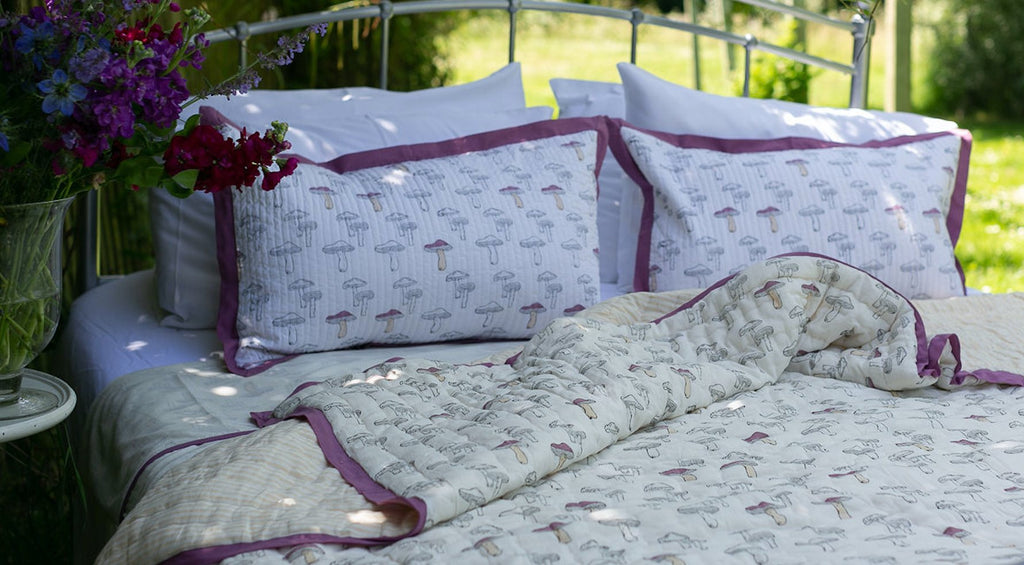 block printed quilts draped on a post and rail fence 