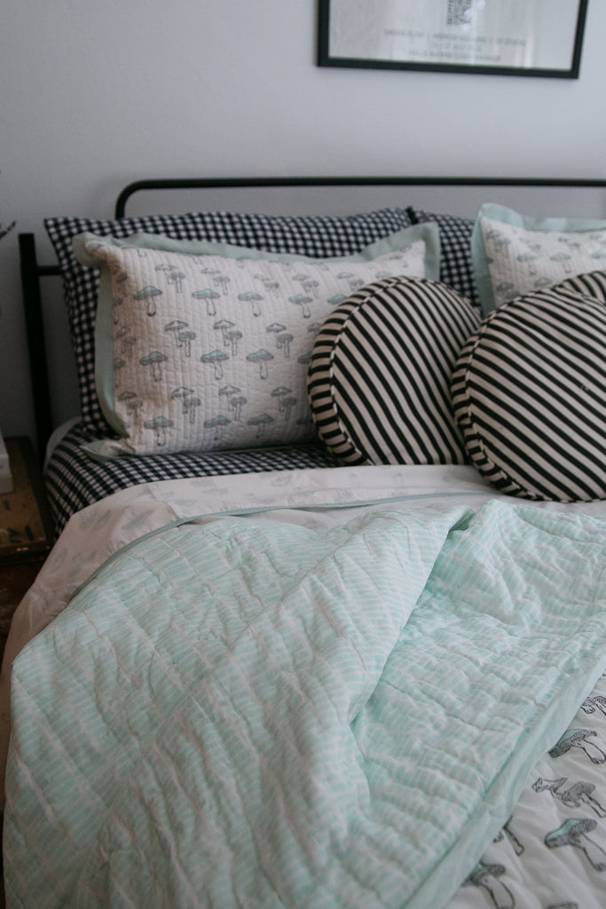 black and white gingham bedding and a mushroom printed quilt and cushions 