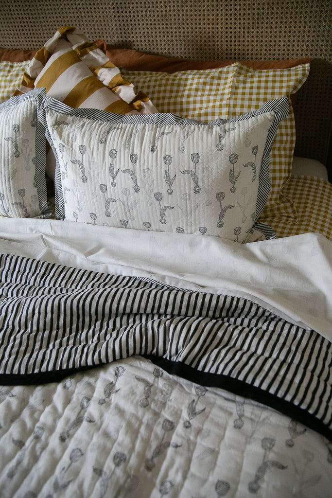 block printed quilt and matching cushion on a bed