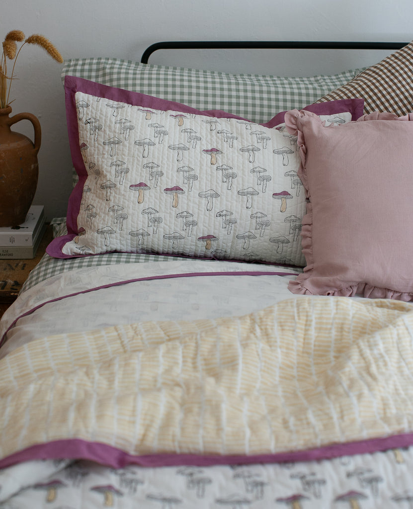 bed set on a bed in an aubergine mushroom design, block printed.