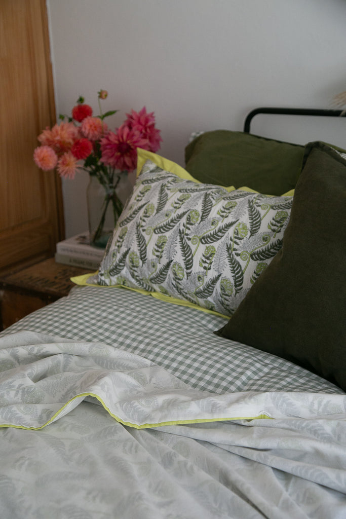 detail of a fern printed dohar with a vase of dahlias in the background