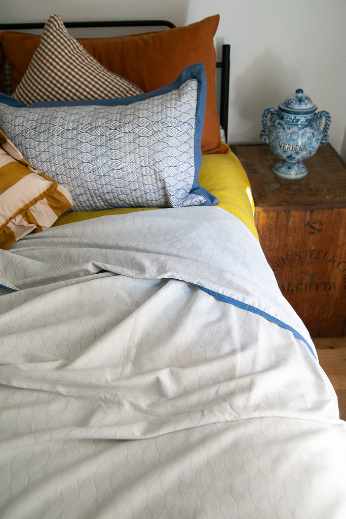 Doahar on a bed with a blue pot on the bedside wooden box