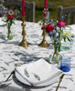 close up of a feather block printed napkin on a table with a matching tablecloth and flowers 