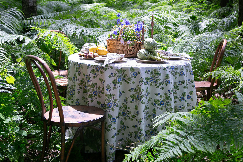 A round table and chair set amongst ferns dressed with a block printed tablecloth 