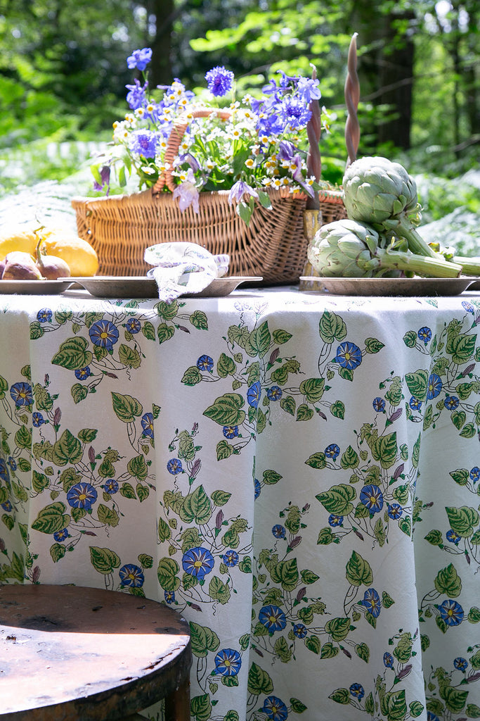 close up of a block printed tablecloth and a basket of blue flowers 