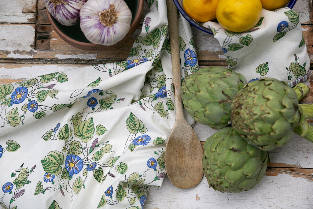 blcok printed teatowel on a wooden board with garlic, artichokes and lemons,