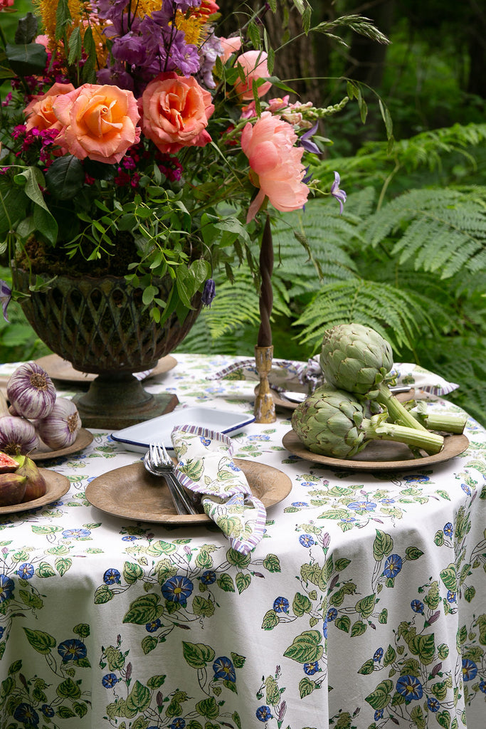 Close up of block printed tablecloth and napkins to match in blues, lilacs and greens on an off white background