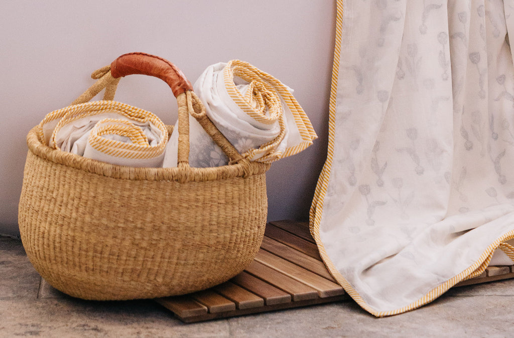 two dohars rolled up in a basket and a detail of a yellow and white striped border on a tulip printed dohar 