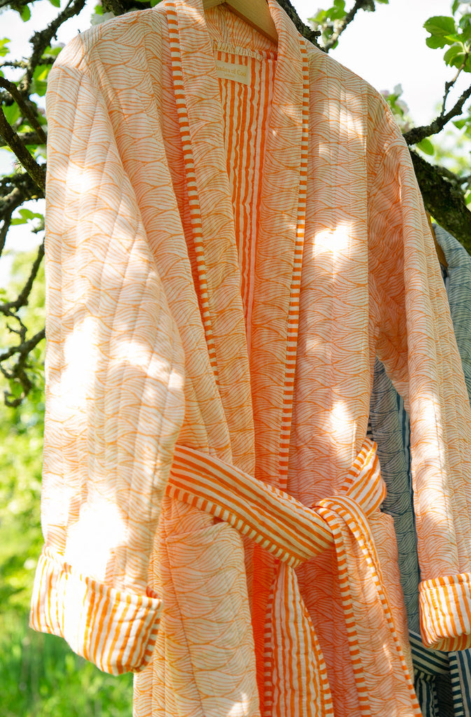 Block printed quilted robe in a tangerine wave design  close up 