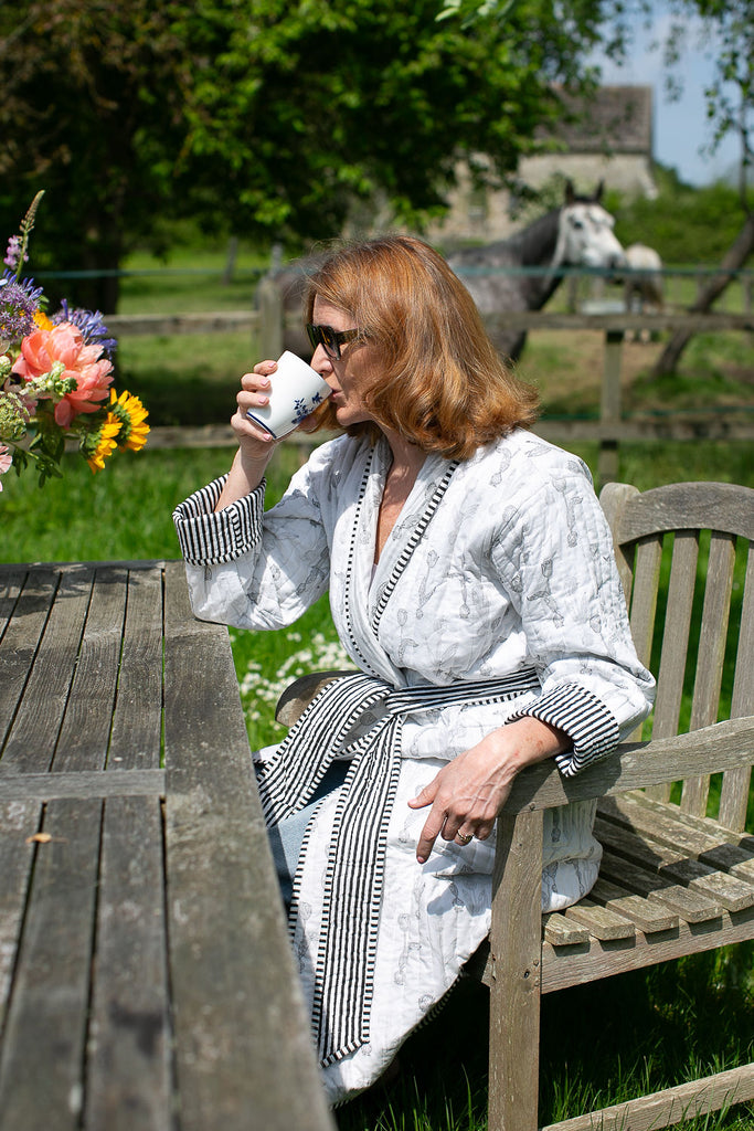 lady having a coeffee in the garden wearing a block printed quilted dressing gown 