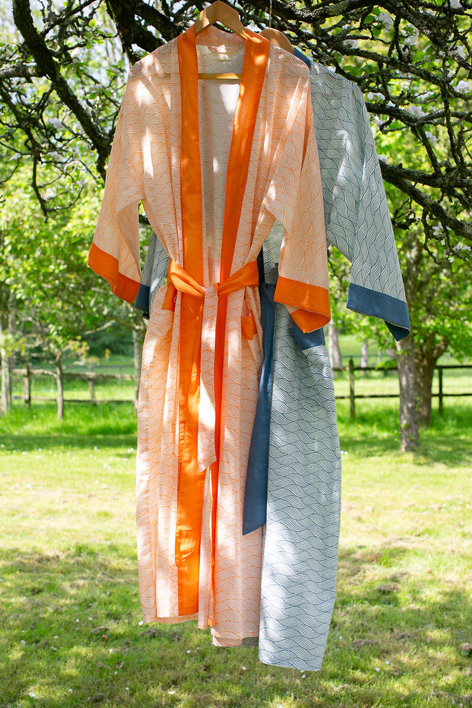 block printed cotton kimono robes in Indigo and Tangerine hanging from a branch in an  apple tree