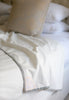 Close-up of a white Dohar Blanket with decorative striped edging on a bed.