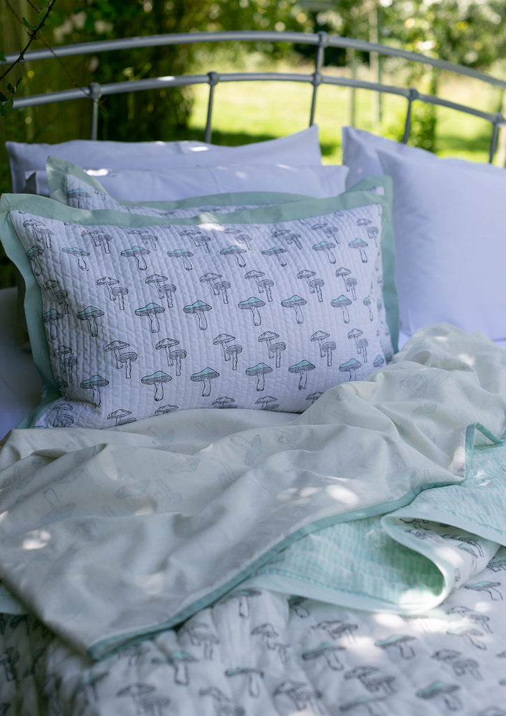 mushroom printed cotton bedlinen on a bed outside 