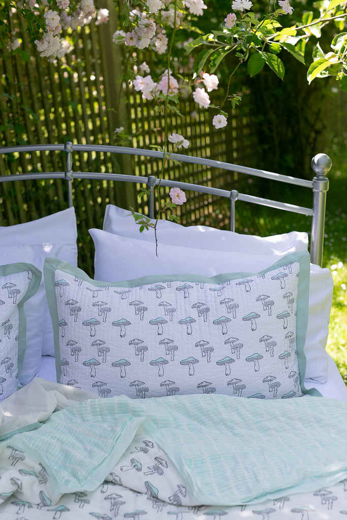 quilt and cushion on a metal bed outside 