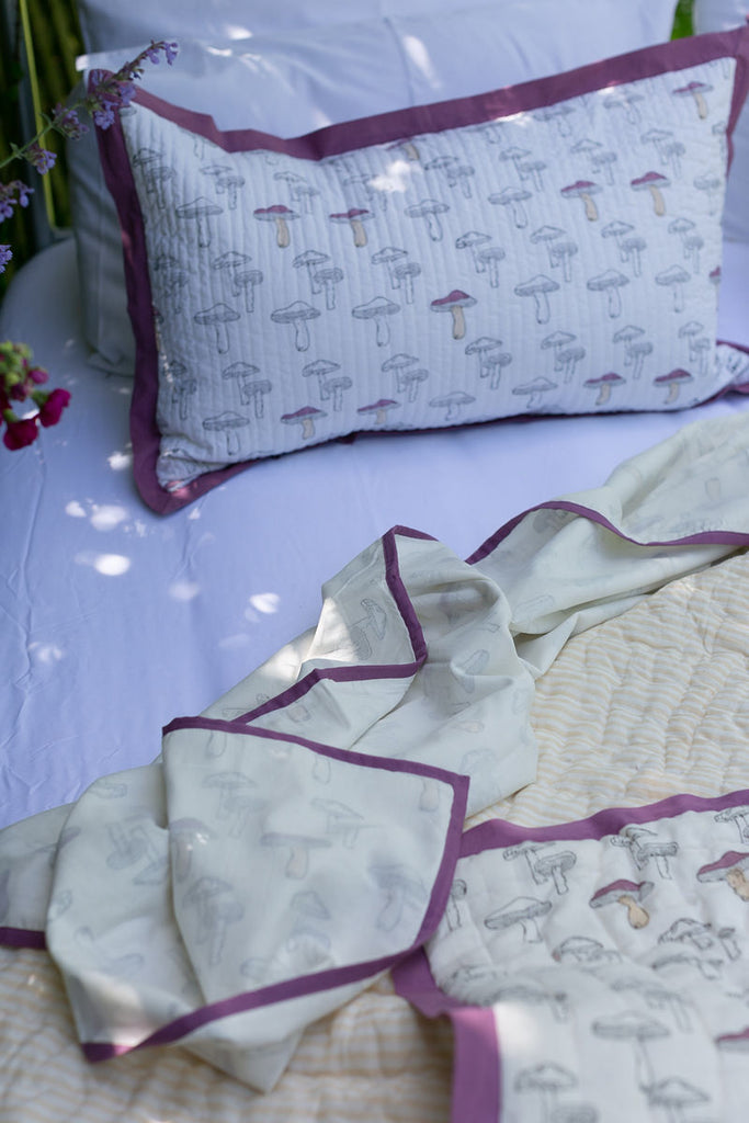 aubergine mushroom design cotton bedlinen on a bed outside 