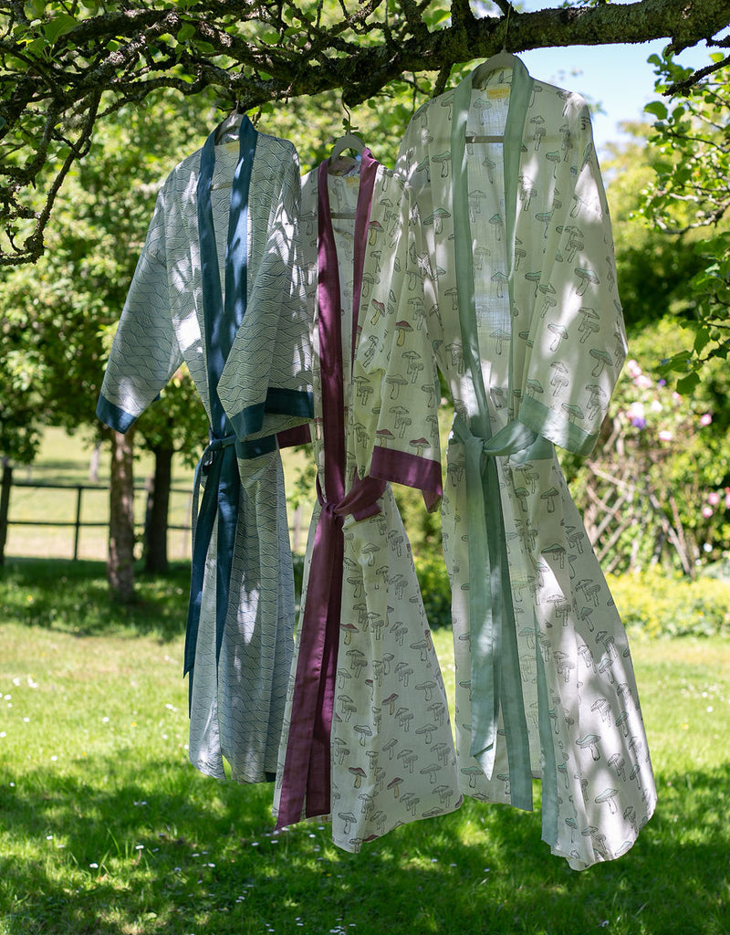 three block printed kimono robes hanging from a tree branch 