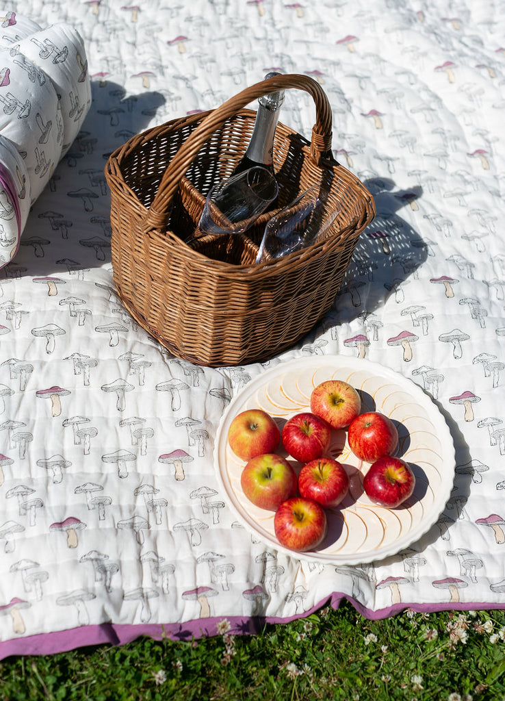 detail of a picnic rug with a cane basket apples and a bottle of wine 