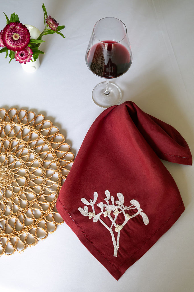 table setting of a red napkin, a glass of wine and a small vase of flowers 