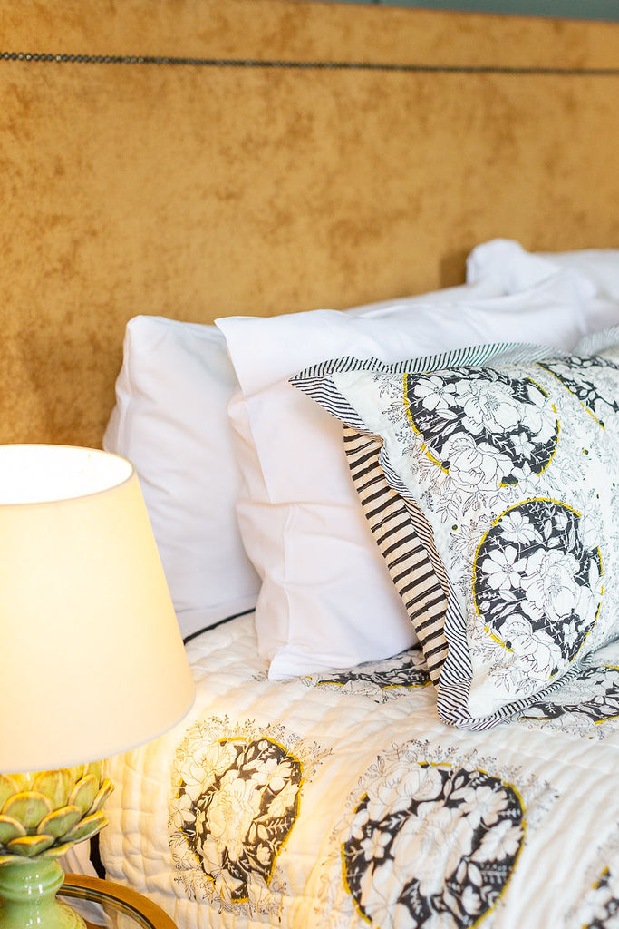 detail of a block printed cushion and quilt on a bed 