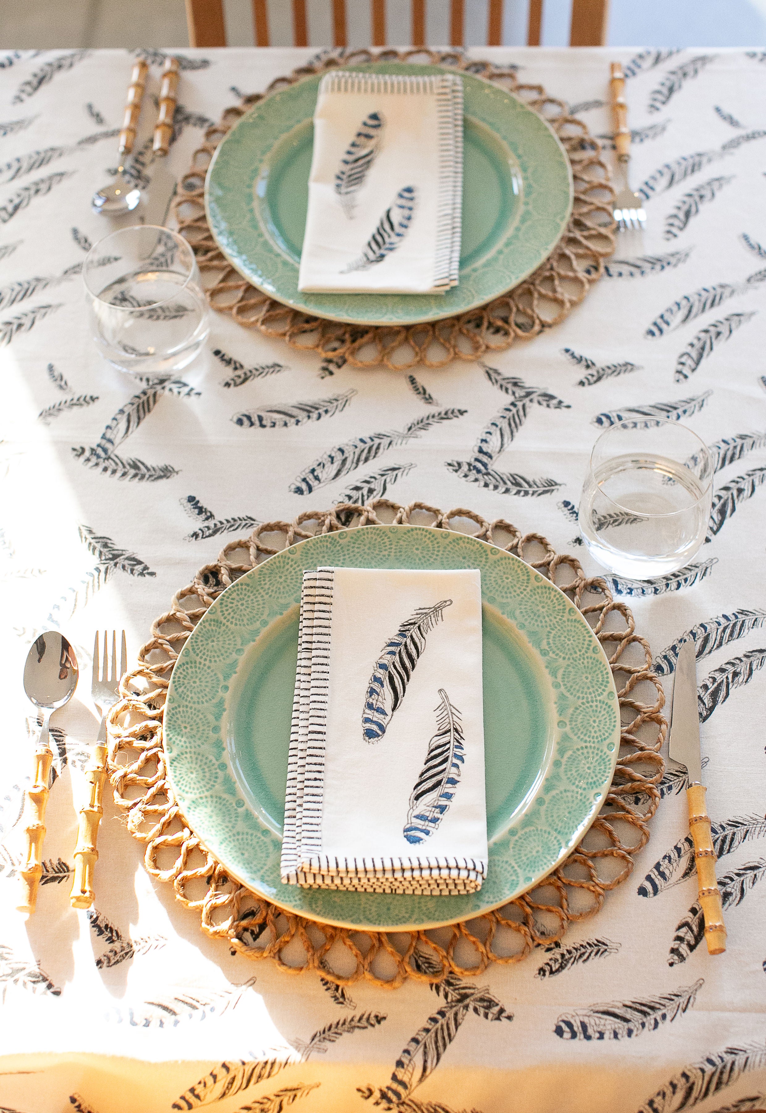 table setting of mint green plates a feather print tablecloth and matching napkins 
