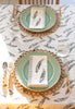 table setting of mint green plates a feather print tablecloth and matching napkins 