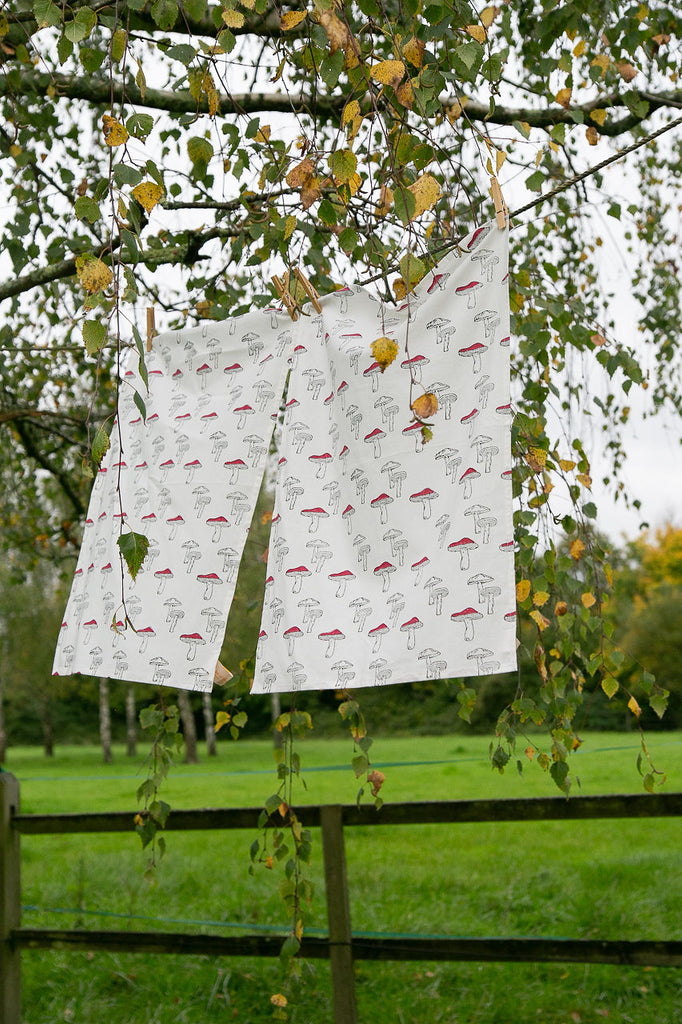 two block printed tea towels, in a mushroom design, hanging from a washing line