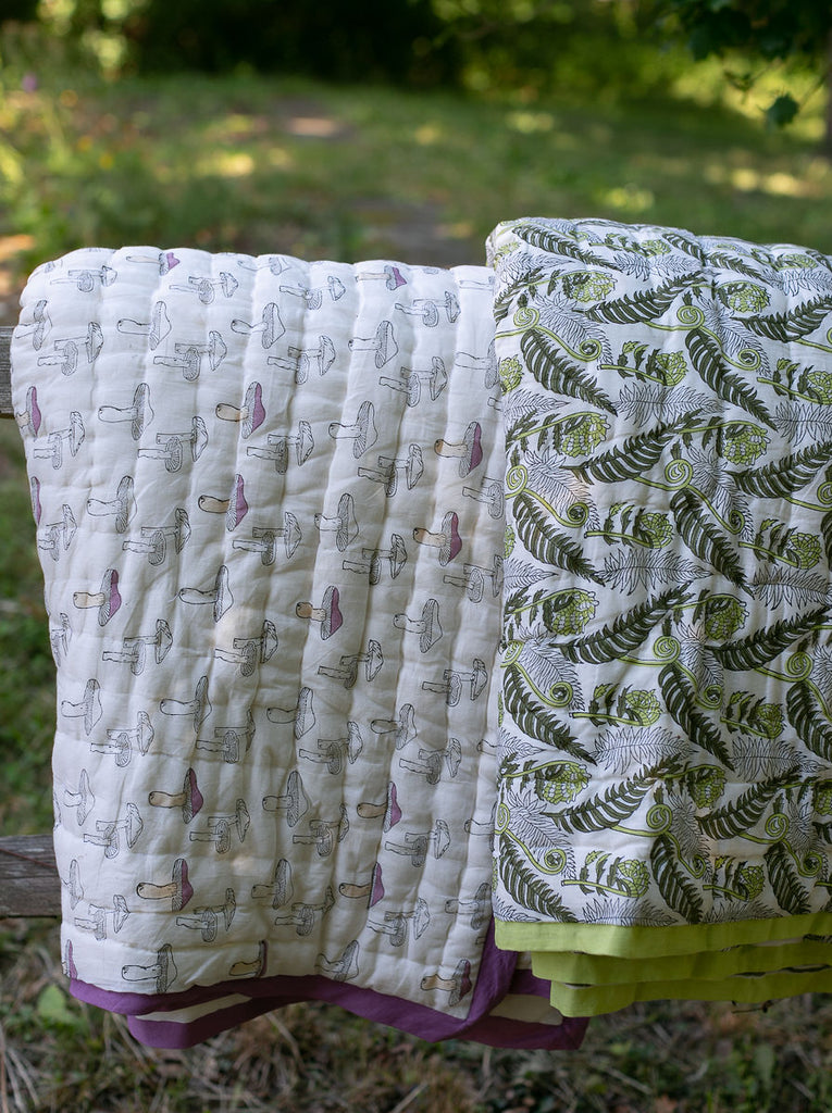 two quilts hung over a fence 